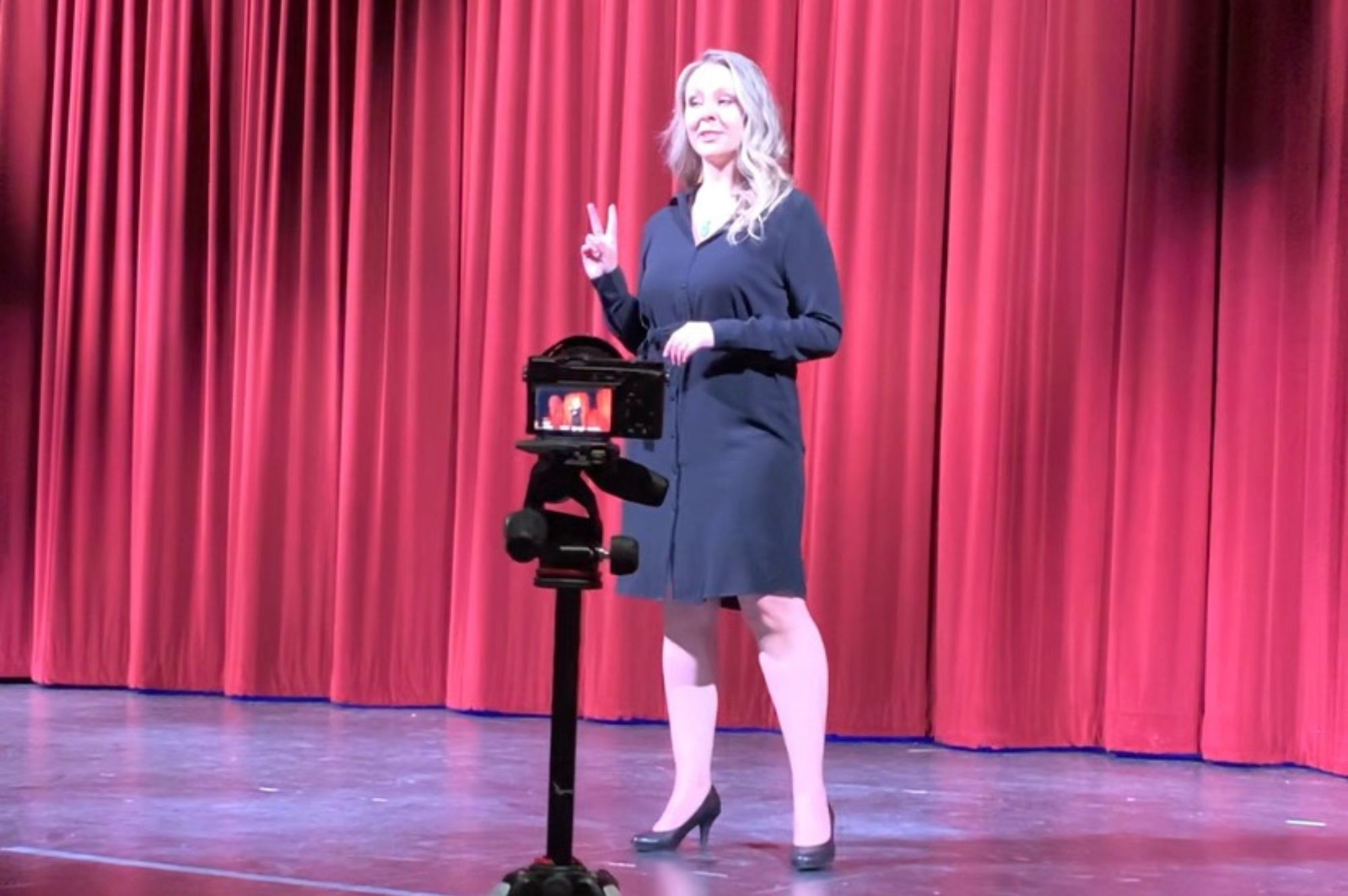 Kady on Stage 1 2000 X 1330 Kady in a black dress on Stage speaking in front of a red curtain